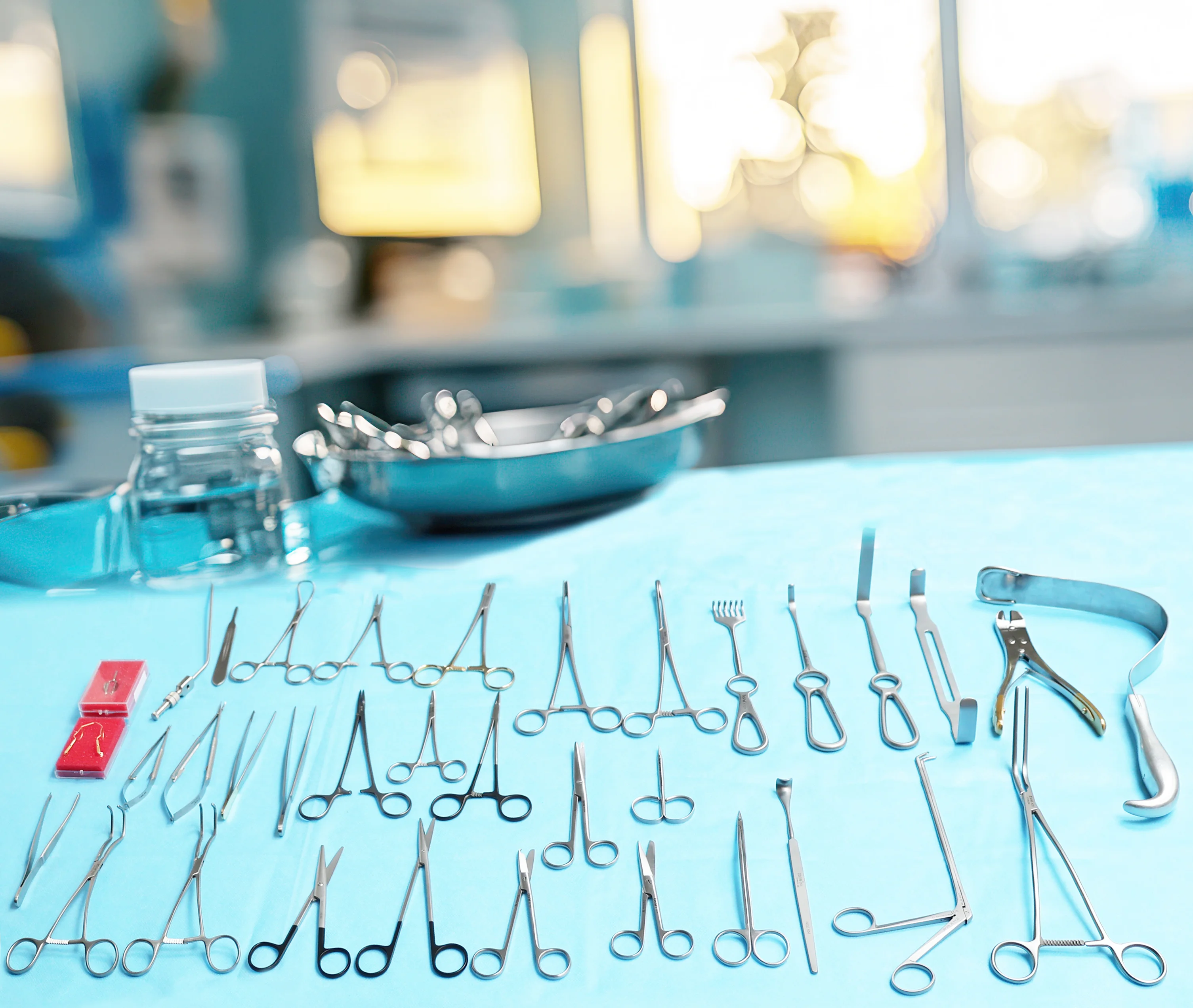 Surgical instruments arranged on a blue surgical drape with warm bokeh